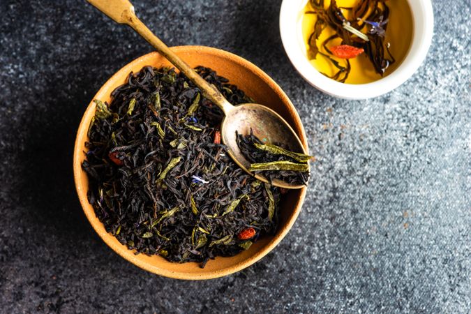 Fragrant loose leaf tea in bowl on counter with cup