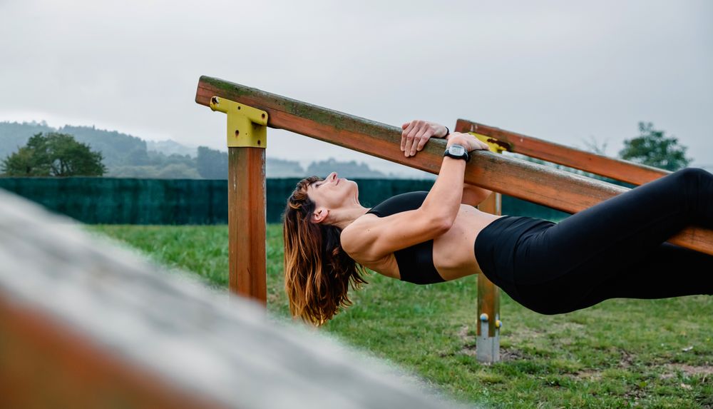 Sportswoman training hanging on a wooden bar