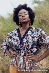 Woman with afro hair wearing patterned shirt standing outdoor 4mB3vb