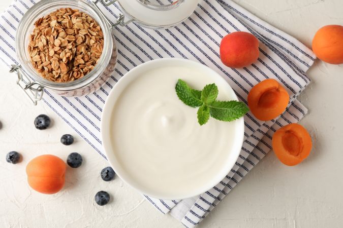 Composition with granola, yogurt and fresh fruits on cement background