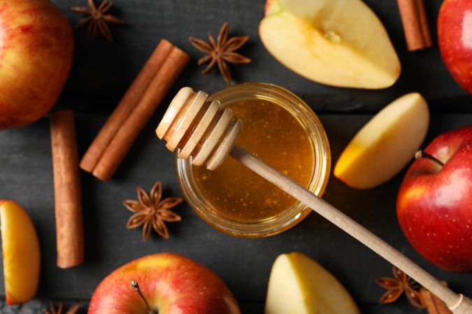 Top view of autumnal apples and cinnamon sticks on dark wooden table