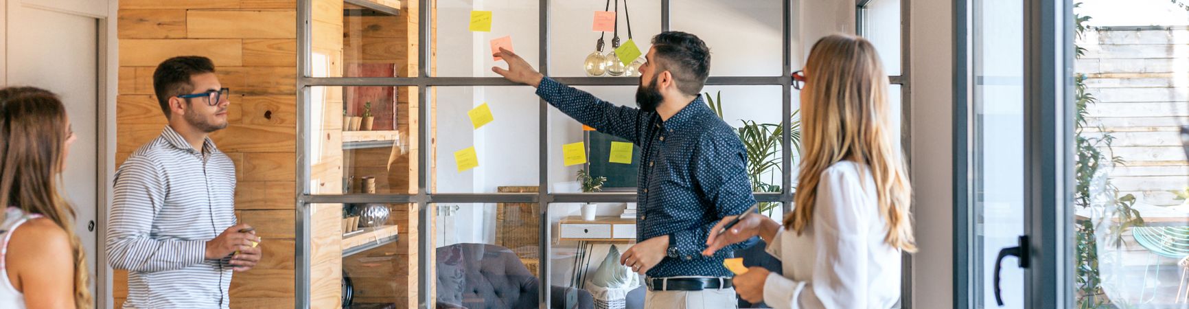 Business people in a work meeting placing sticky notes on the wa