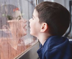 Boy breathing on wet glass