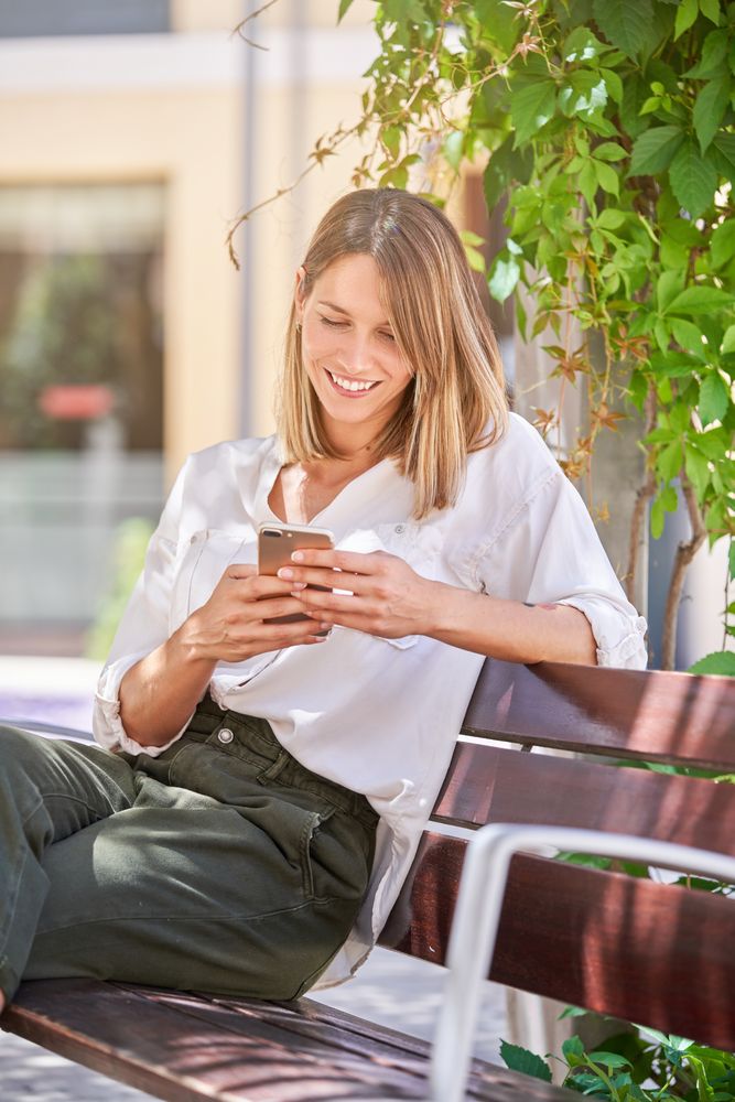 Smiling woman with smartphone on bench
