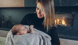 Mother hugging her baby in front of fireplace