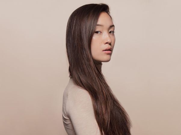 Profile shot of Korean woman with a long straight hair looking at camera