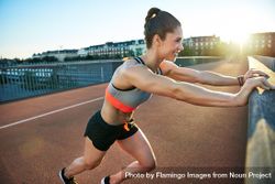 Smiling fit woman warming up with stretched on bridge before morning workout 0VDY34