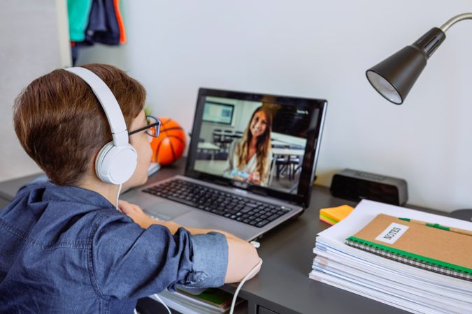 Boy with headphones receiving class at home with laptop from his bedroom