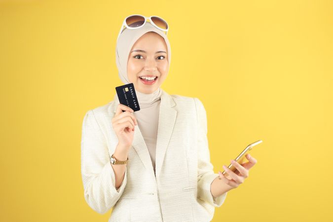 Young Asian Muslim Woman Smiling While Holding Credit Card and Smartphone