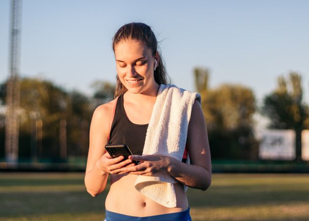 An athletic woman resting with her smartphone after running.