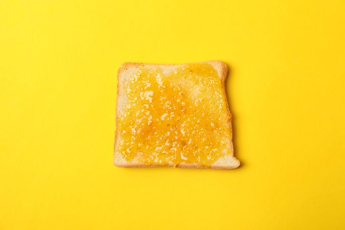 Toast with orange jam on yellow background, close up