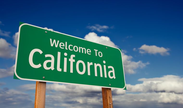 Welcome To California Green Road Sign Over Blue Sky with Some Clouds.