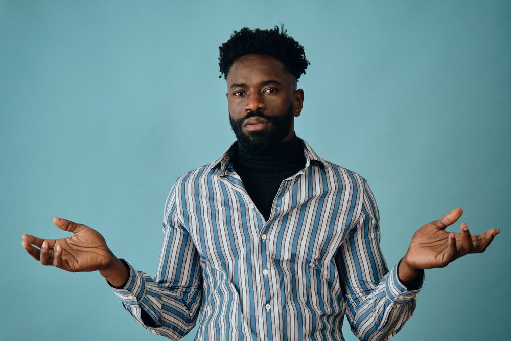 Serious Black man in striped shirt and jeans with open arms
