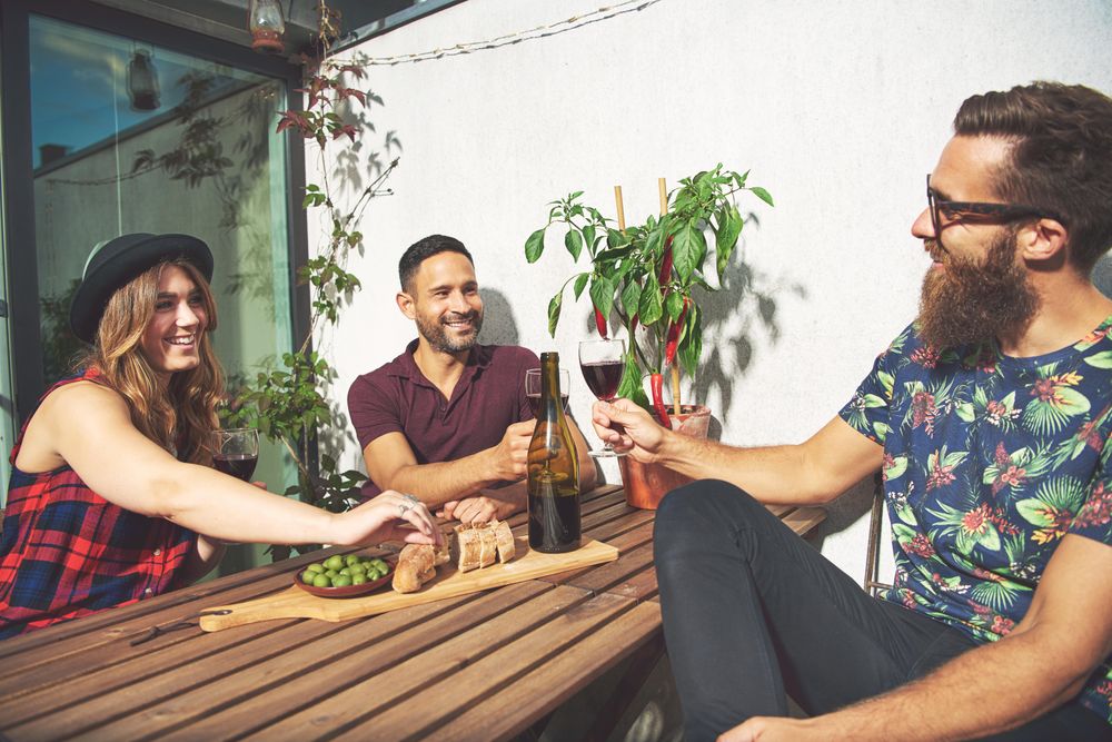 Friends on patio with red wine, bread and olives