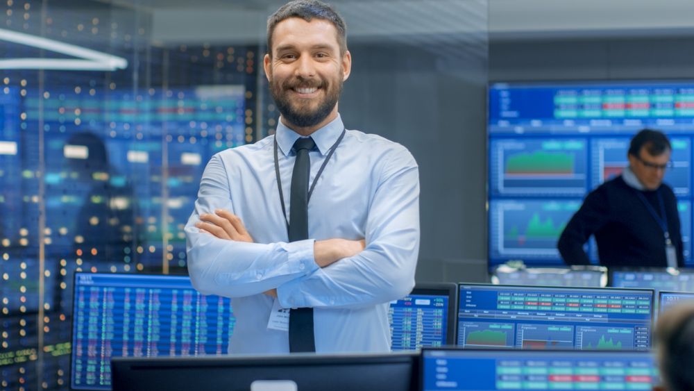 Successful Male Stock Trader Crosses Arms and Smiles at the Camera.