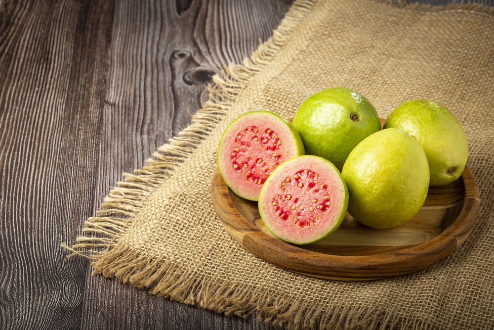 Fresh sliced guavas on wooden table.