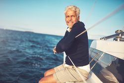 Man looking ahead while sitting on edge of sailing yacht on clear day
