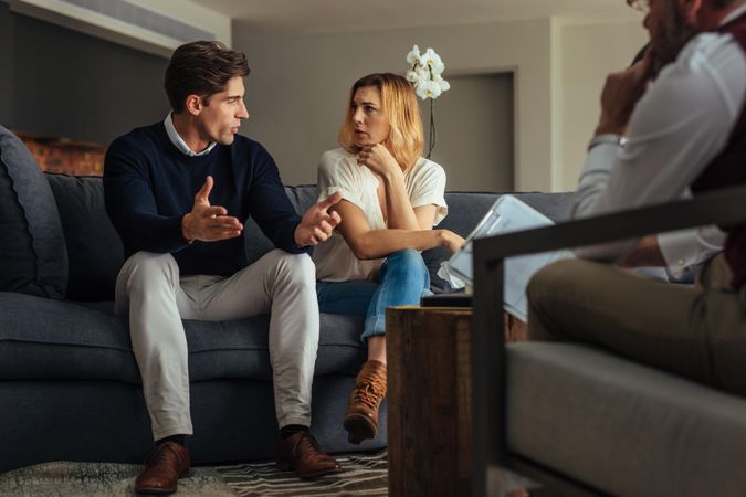 Married couple talking to each other during therapy session with therapist