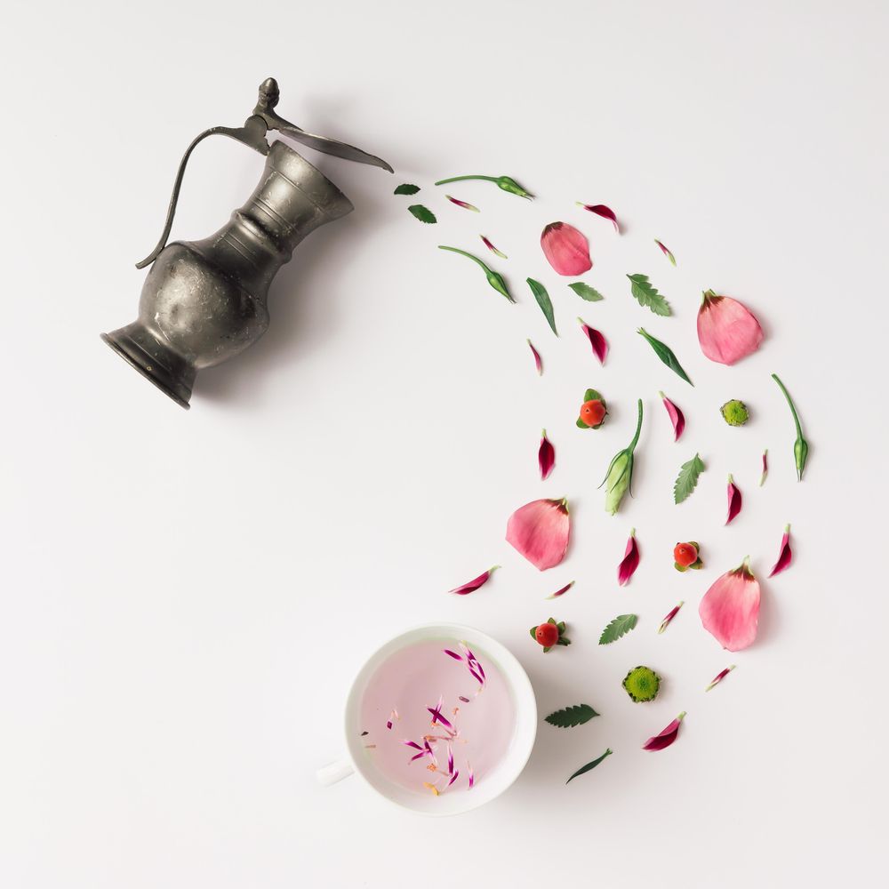 Tea pot pouring various natural herbs with cup of herbal water