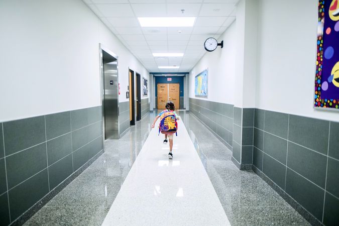 Back view of young student walking in the hallway
