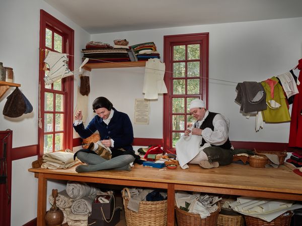 Two tailors hand sewing garments in Colonial Williamsburg, Virginia