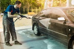 A man washes a car in a manual car wash. Clear car