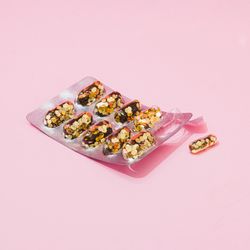 Pill packer with glitter in place of pills on pink background