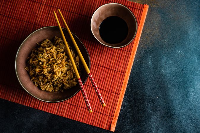 Bowls  of rice with chopsticks on red table mat