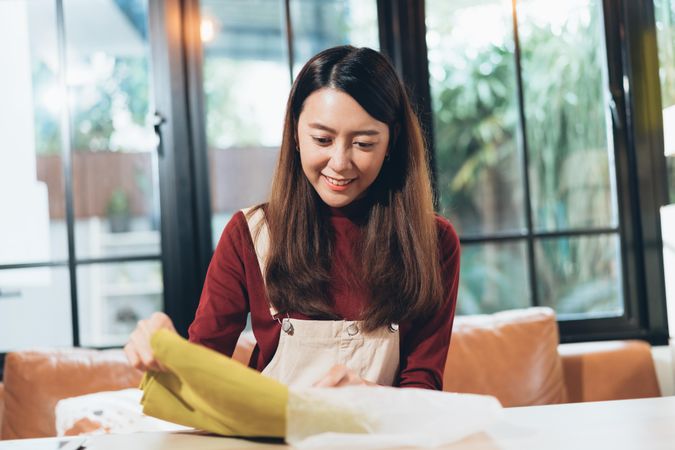 Asian woman taking fabric out of bag