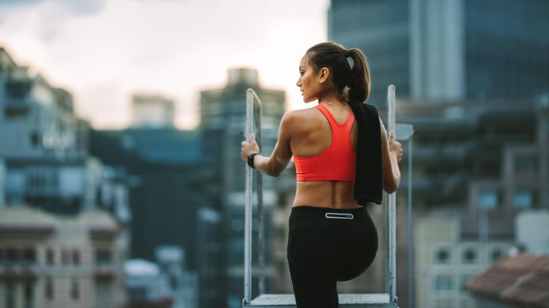 Female athlete standing on rooftop staircase looking away
