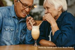 Closeup of happy couple in love at cafe drinking cold coffee from same glass bGMxl5