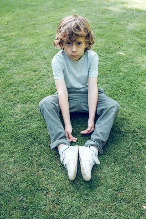 Cute boy sitting on grassy meadow
