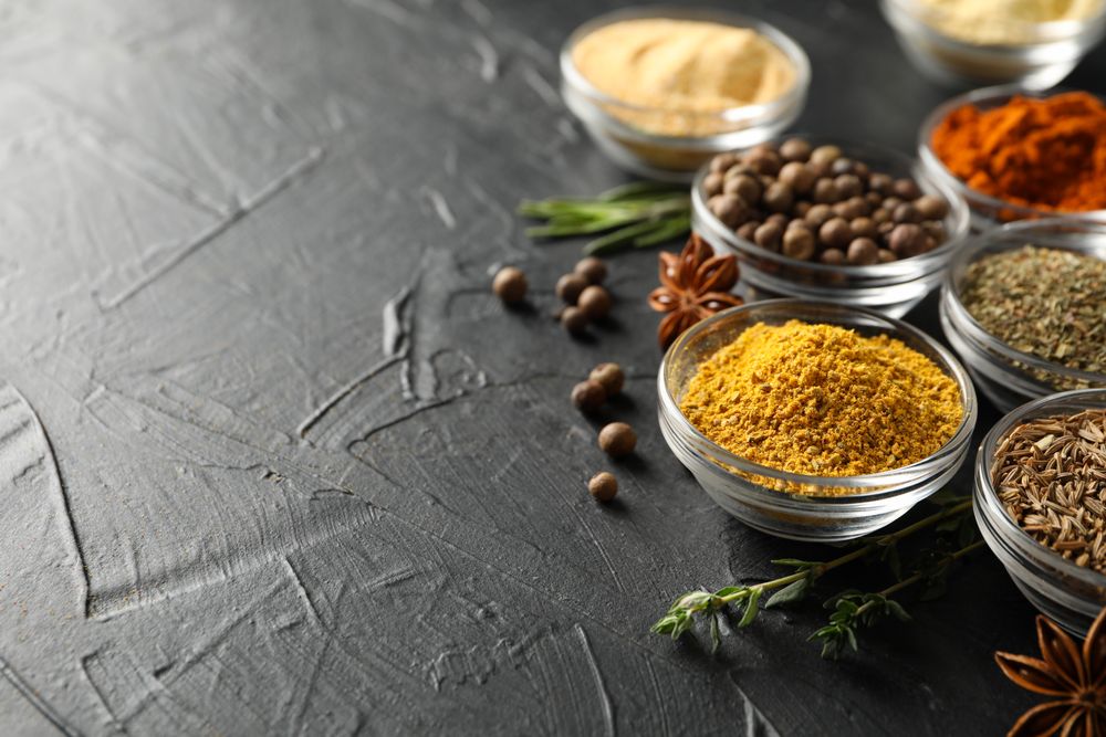 Glass bowls full of spices on dark table with copy space
