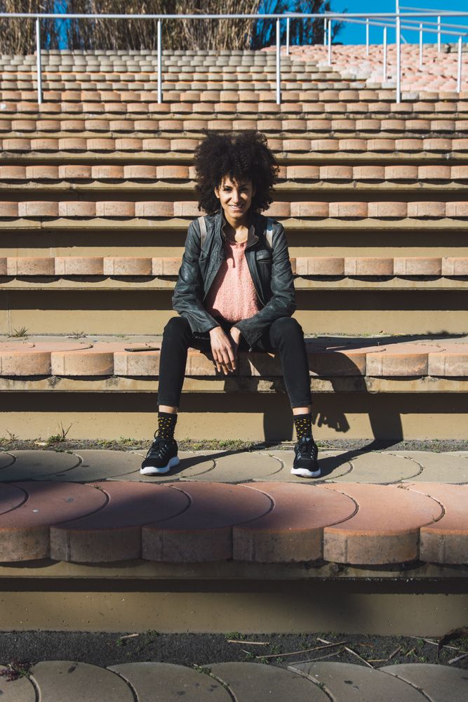 Woman with afro hair sitting on the steps of a stadium
