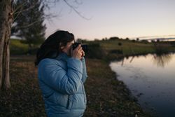Photographer woman taking photos of a lake at sunset