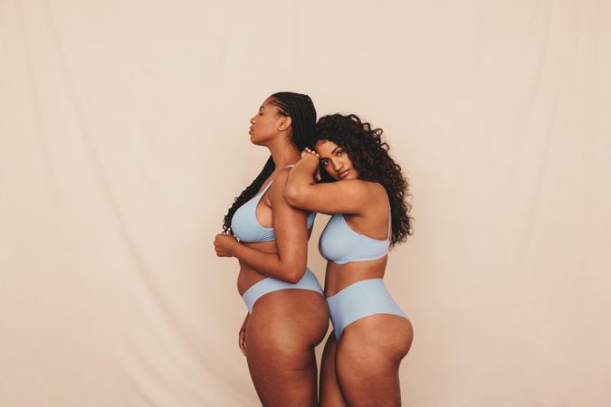 Confident best friends modeling together in studio showing their natural curves