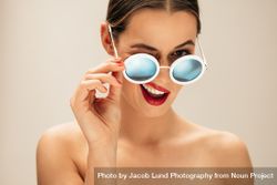 Portrait of beautiful young woman with sunglasses winking bxBLv5