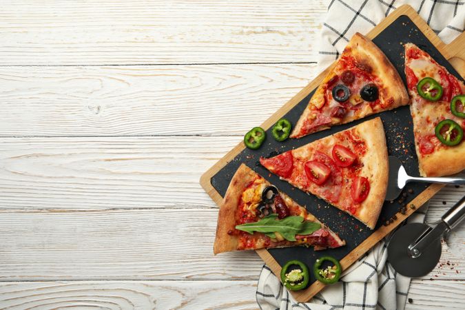 Board with tasty pizza slices on wooden background