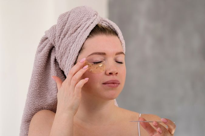 Applying eye patches in skincare routine.