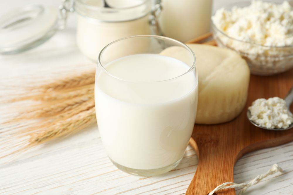 Spikelets of wheat, dairy products and board on wood background, closeup