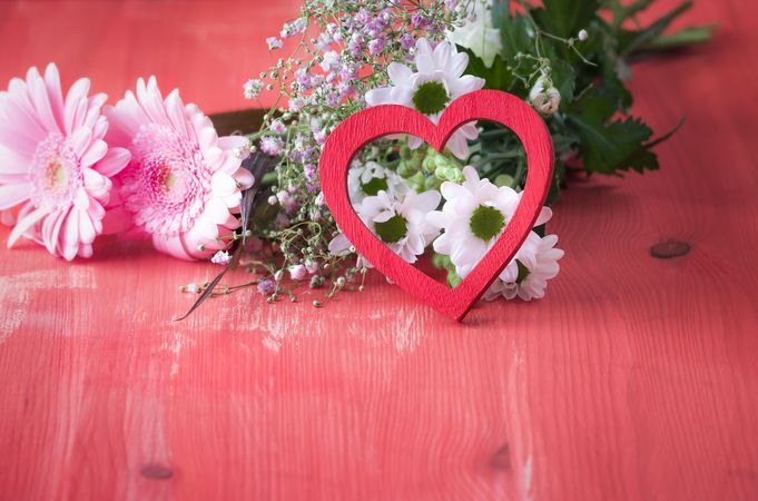 Red heart leaned on flowers for Valentine’s Day concept