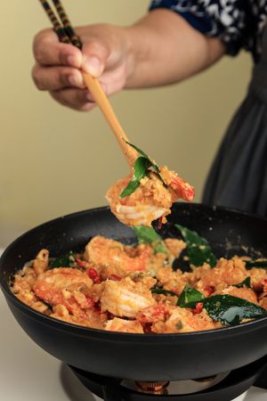 Female Hand Cooking Shrimp with Salted Egg Sauce using Long Chopstick on Pan