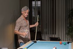 Mature man having drink while playing pool