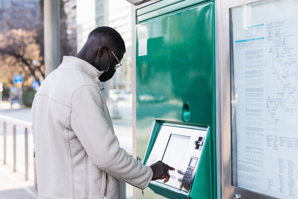 Black businessman touching screen of ATM in town