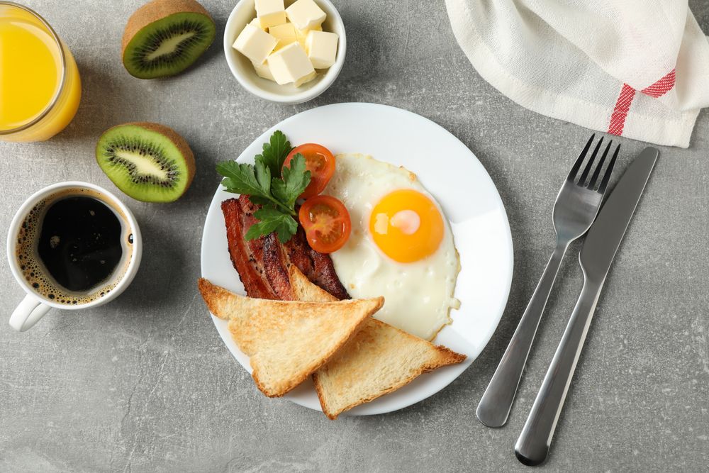 Top view of breakfast for one with eggs, toast, bacon and coffee