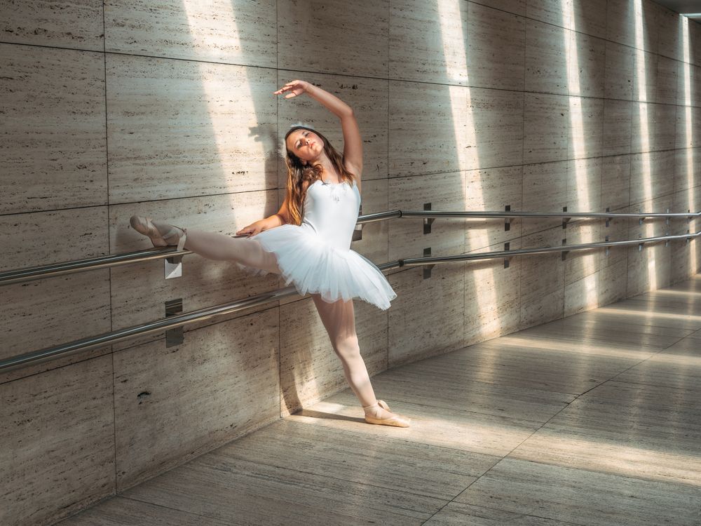 Ballerina doing ballet posing at rail in classroom
