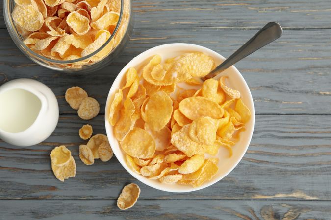 Milk, bowl and jar of muesli on wooden background