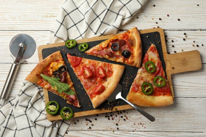 Board with tasty pizza slices on wooden background