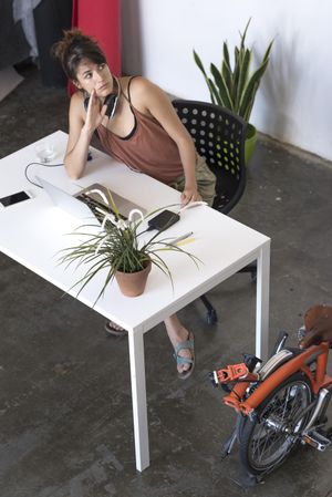 Female thinking about something at desk with laptop and plant