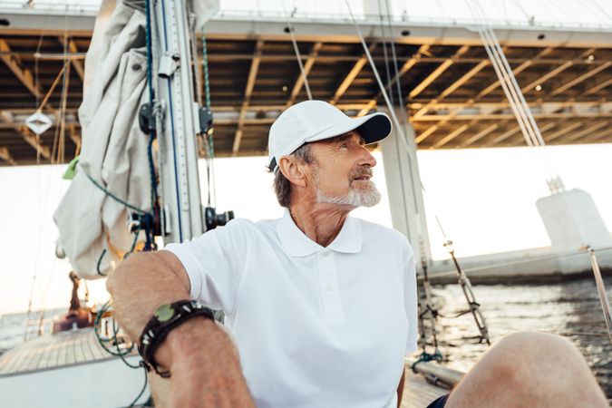 Mature captain relaxing on sailboat at sunset